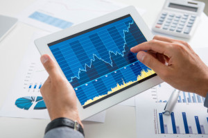 man looking at stocks graphs on tablet
